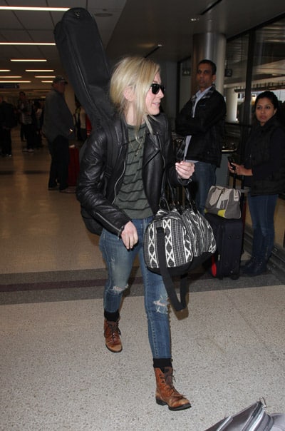 Эмили Кинни в аэропорту одета в рванные синие джинсы, серая кофта и черная куртка косуха